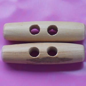 May include: Two wooden toggle buttons, each with two holes. The buttons are light brown and have a smooth finish.