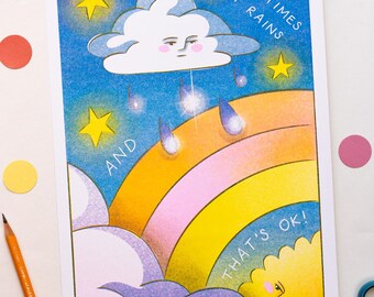 May include: A rectangular art print featuring a blue night sky with yellow stars, a rainbow, and a cloud with a face. The text reads: SOMETIMES IT RAINS AND THAT'S OK! A yellow sun with a face is visible in the bottom right corner, and blue raindrops fall from the cloud.