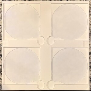 May include: A white, square, four-sectioned tray with rounded cutouts. Each section features a circular indentation with a small, rounded tab. The tray is designed to hold and organize small, round objects.