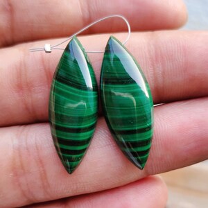 May include: A pair of green malachite gemstone earrings in a marquise shape. The earrings are a deep green color with dark green veins.