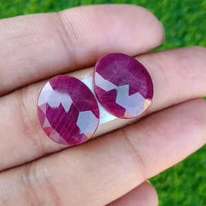 Op de afbeelding: Twee ronde, gefacetteerde robijn edelstenen met een dieprode kleur. De edelstenen zijn ongeveer 1 cm in diameter.