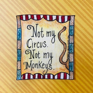 May include: A yellow and brown illustrated card with a red and white striped border. The card features a brown monkey tail and the text "Not my circus. Not my monkeys."