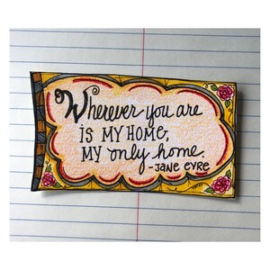 May include: A yellow and red hand-drawn card with a cloud-shaped design. The card features the quote "Wherever you are is my home, my only home." - Jane Eyre.