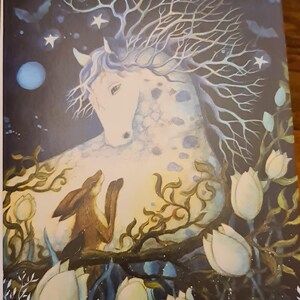 Peut inclure: Une peinture à l'aquarelle d'un cheval blanc avec un arbre qui pousse sur sa tête. Le cheval est entouré de fleurs blanches et un petit lapin brun le regarde. Le fond est bleu foncé avec des étoiles blanches.