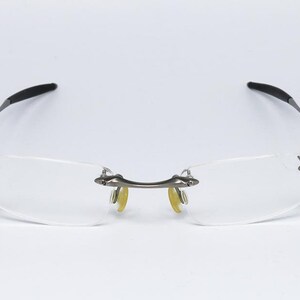 May include: A pair of rimless eyeglasses with a silver frame and clear lenses.