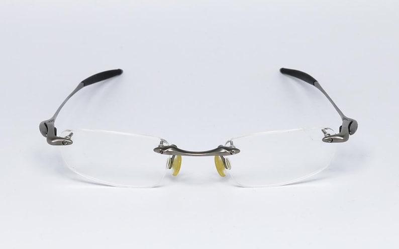 May include: A pair of rimless eyeglasses with a silver frame and clear lenses.