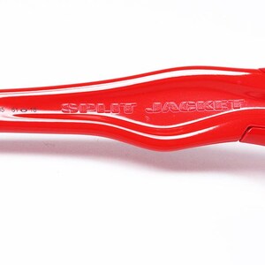以下が含まれることがあります： 「SPLIT JACKET」の文字がエンボス加工された赤いプラスチック部品のクローズアップ。部品は滑らかな曲線デザインで、黒いラバーグリップとシルバーの留め具が付いています。「009099-05 610 18」の製品コードも確認できます。