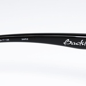 Puede incluir: Varilla de gafas negra con el nombre de la marca "Backhand" en escritura blanca. La varilla tiene los n&uacute;meros "009178-07 59 17 138" y la palabra "SAMPLE" impresa.