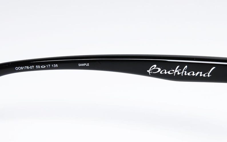 Puede incluir: Varilla de gafas negra con el nombre de la marca "Backhand" en escritura blanca. La varilla tiene los n&uacute;meros "009178-07 59 17 138" y la palabra "SAMPLE" impresa.