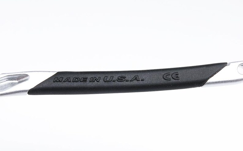 May include: Close-up of a silver and black arm of a pair of glasses with the text "MADE IN U.S.A." and "CE" printed on the arm.