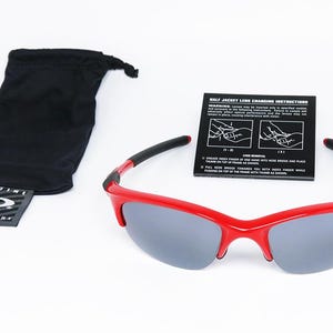Puede incluir: Gafas de sol rojas con lentes grises, patillas negras y una bolsa negra con cord&oacute;n. Tambi&eacute;n se incluye una tarjeta negra con instrucciones. Las gafas de sol tienen el nombre de la marca en la montura.