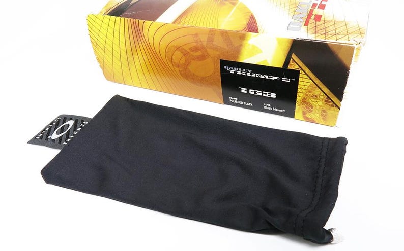 May include: An unopened box of Oakley sunglasses with a black microfiber bag and a small tag. The box has a gold and brown design. The tag and box indicate the sunglasses are "Polished Black" and "Black Iridium".