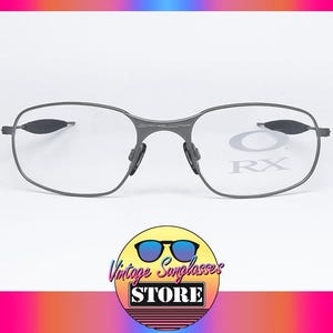 May include: Gray metal frame eyeglasses with clear lenses. The lenses have the text "RX" printed on them.
