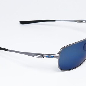 May include: Sleek, modern sunglasses with a silver frame and blue lenses. The temples have black tips for added comfort. The lenses are a vibrant blue, offering a stylish look. These sunglasses are designed for both fashion and eye protection.