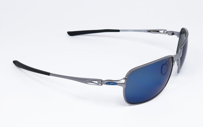 May include: Sleek, modern sunglasses with a silver frame and blue lenses. The temples have black tips for added comfort. The lenses are a vibrant blue, offering a stylish look. These sunglasses are designed for both fashion and eye protection.