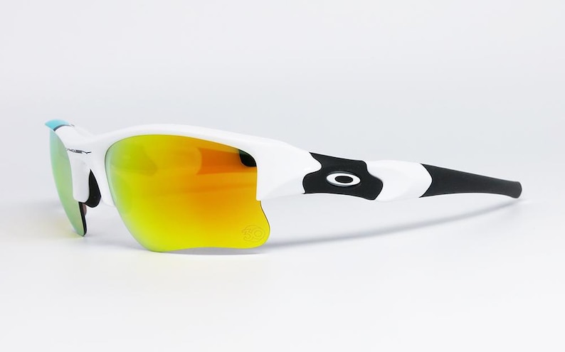 May include: White and black sunglasses with orange and yellow lenses. The sunglasses have a sleek design with a black and white pattern on the arms and a small blue accent. The lenses have a mirrored finish.
