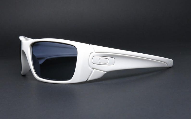 May include: White sunglasses with dark lenses. The sunglasses have a rectangular frame and a sleek, modern design. The arms of the sunglasses are thick and curve slightly. The lenses are dark, providing protection from the sun.