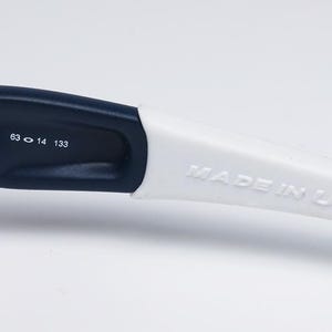 以下が含まれることがあります： 白とネイビーブルーのメガネアームのクローズアップ。テキスト「MADE IN U.S.A.」は白いアームにエンボス加工されています。アームには「24-321 63 14 133」の数字も印刷されています。
