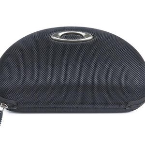 May include: A black zipped case for sunglasses with a silver metal ring on the top.