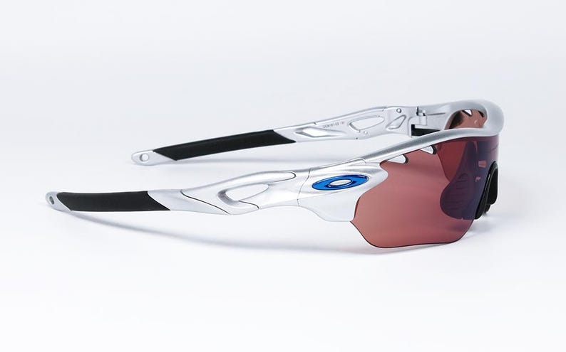 May include: Silver and black wraparound sunglasses with a blue accent on the frame and brown lenses.