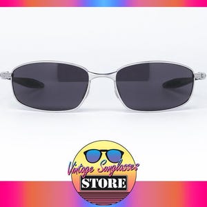 May include: Silver-framed sunglasses with dark lenses. The glasses have a sleek, modern design. The image also includes a logo for "Vintage Sunglasses Store".