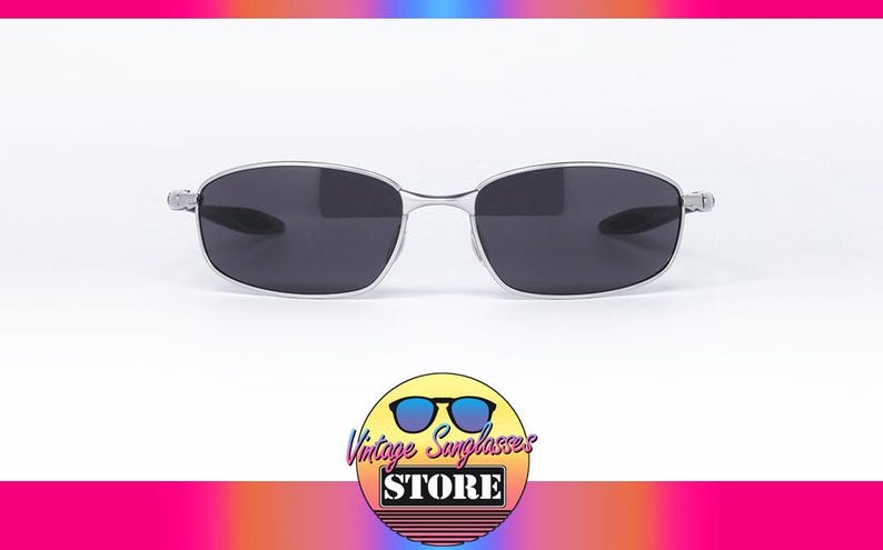 May include: Silver-framed sunglasses with dark lenses. The glasses have a sleek, modern design. The image also includes a logo for "Vintage Sunglasses Store".
