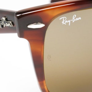 Peut inclure: Gros plan sur une paire de lunettes de soleil Ray-Ban en &eacute;caille de tortue brune avec des verres bruns. Le logo Ray-Ban est visible sur la lentille droite.