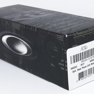 K&ouml;nnte beinhalten: Eine schwarze rechteckige Box mit einem silbernen ovalen Emblem. Die Box hat ein gemustertes Design und ein wei&szlig;es Etikett mit Text und einem Barcode. Das Etikett enth&auml;lt die Texte "OX3232" und "Base Plane (54) Matte Midnight".