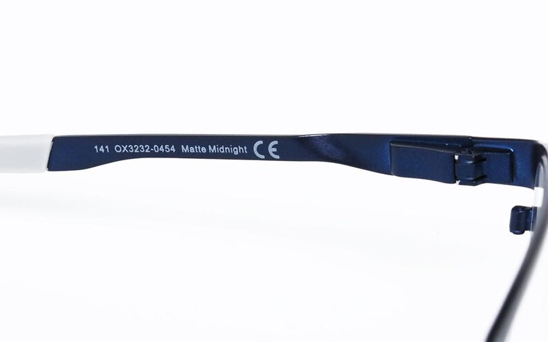 K&ouml;nnte beinhalten: Nahaufnahme des B&uuml;gels einer Brille. Der B&uuml;gel ist matt marineblau mit dem Text "141 OX3232-0454 Matte Midnight" aufgedruckt. Das Ende des B&uuml;gels ist wei&szlig;. Das CE-Zeichen ist sichtbar.