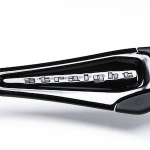 May include: Close-up of a black and silver sunglasses arm. The word "STRAIGHT" is displayed in silver lettering on a black, glossy surface. The arm is made of black plastic and has a sleek, modern design.