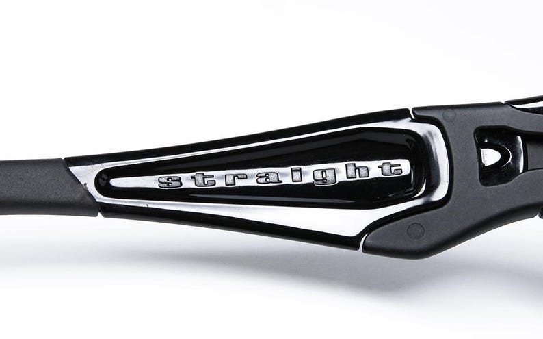 May include: Close-up of a black and silver sunglasses arm. The word "STRAIGHT" is displayed in silver lettering on a black, glossy surface. The arm is made of black plastic and has a sleek, modern design.
