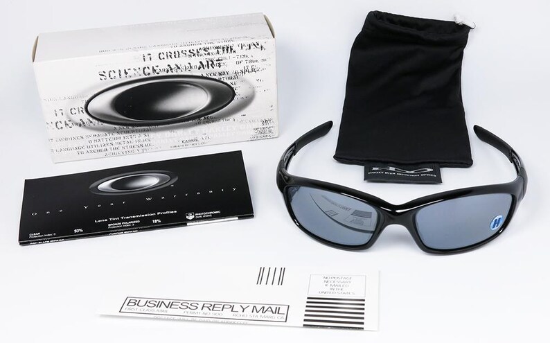 May include: Black sunglasses with gray lenses, a black carrying pouch, and a box with the brand logo. The sunglasses are displayed on a white surface. Also included is a warranty card and a business reply mail envelope.