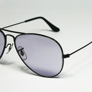 May include: Black aviator sunglasses with a dark gray lens. The sunglasses have a thin metal frame and are in focus.