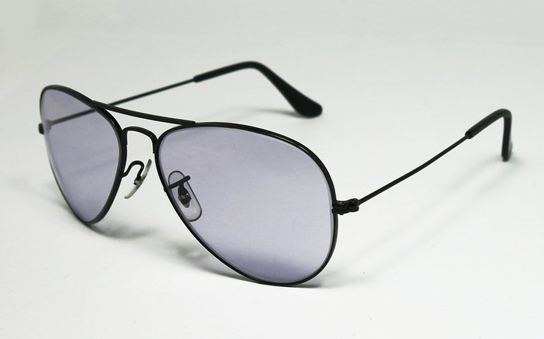 May include: Black aviator sunglasses with a dark gray lens. The sunglasses have a thin metal frame and are in focus.