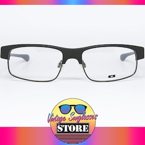 May include: Black rectangular eyeglasses with clear lenses. The glasses have a matte finish and a small logo on the lower right lens. The image includes a logo for Vintage Sunglasses Store.