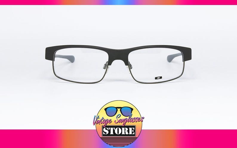 May include: Black rectangular eyeglasses with clear lenses. The glasses have a matte finish and a small logo on the lower right lens. The image includes a logo for Vintage Sunglasses Store.