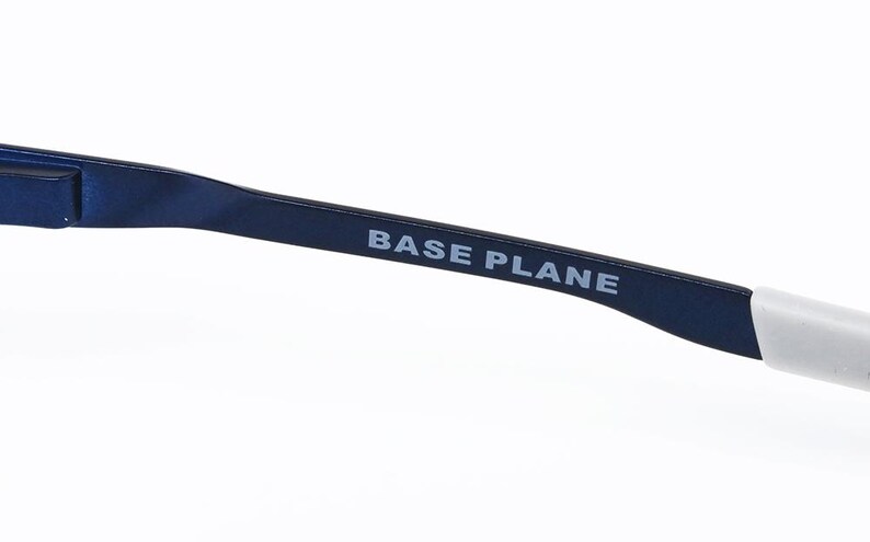 K&ouml;nnte beinhalten: Nahaufnahme eines marineblauen Brillenb&uuml;gels mit dem Text "BASE PLANE" in Wei&szlig;. Der B&uuml;gel hat ein schlankes, modernes Design und eine wei&szlig;e Spitze.