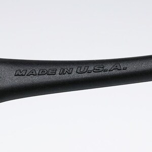 Pu&ograve; includere: Primo piano di un manico nero con la scritta "MADE IN U.S.A." in rilievo. Il manico ha una forma curva e un'estremit&agrave; in metallo color argento.