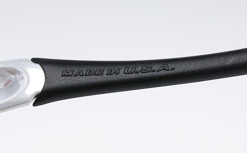 Pu&ograve; includere: Primo piano di un manico nero con la scritta "MADE IN U.S.A." in rilievo. Il manico ha una forma curva e un'estremit&agrave; in metallo color argento.