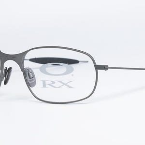 May include: Gray metal frame eyeglasses with clear lenses. The lenses have the text "O RX" printed on them.