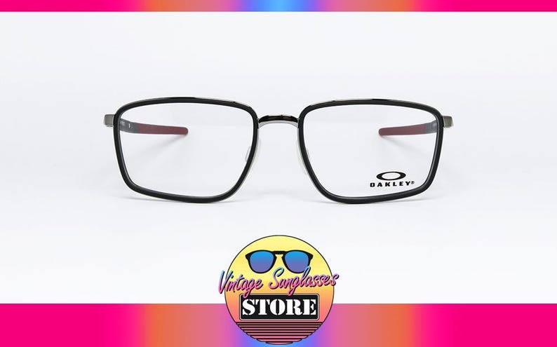 May include: Black framed Oakley eyeglasses with a rectangular shape. The temples have a red accent. The Oakley logo is visible on the right lens. The background is white with a colorful gradient.