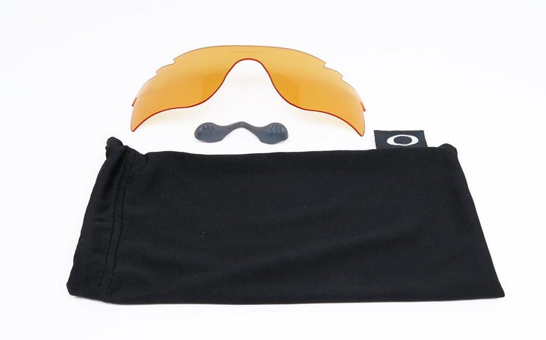 May include: A black microfiber pouch with the Oakley logo, a pair of orange replacement lenses, and two small black nose pads.