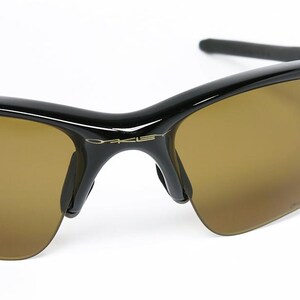May include: Black sunglasses with brown lenses. The sunglasses have a sleek, modern design with a glossy black frame and a subtle logo on the temple. The lenses are a warm brown color, providing a contrast to the black frame.