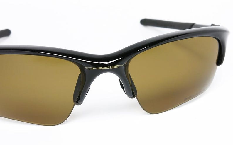 May include: Black sunglasses with brown lenses. The sunglasses have a sleek, modern design with a glossy black frame and a subtle logo on the temple. The lenses are a warm brown color, providing a contrast to the black frame.