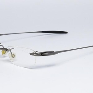 May include: A pair of silver-toned rimless glasses with black temple tips.