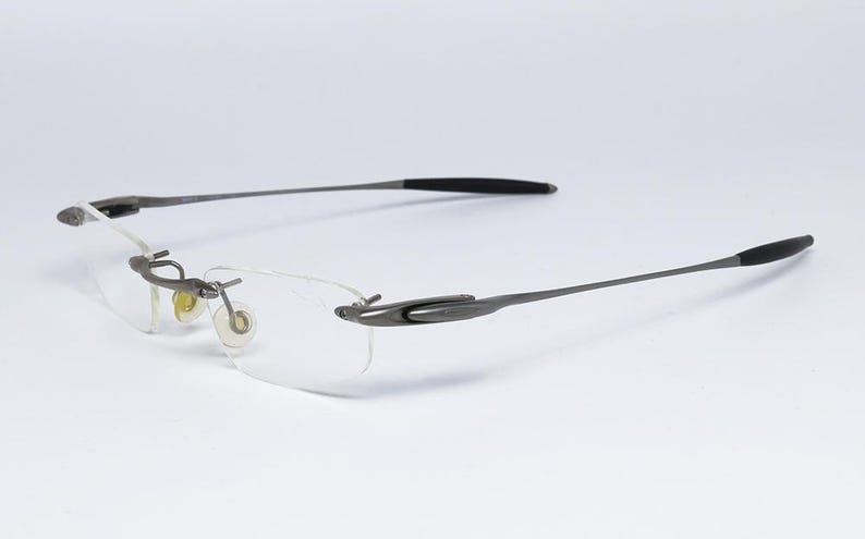 May include: A pair of silver-toned rimless glasses with black temple tips.