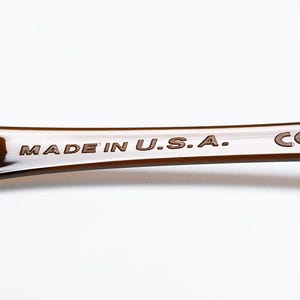 May include: Close-up of a brown, curved object with the text "MADE IN U.S.A." and the letters "CE" etched into the surface. The object has a glossy finish and is set against a white background.