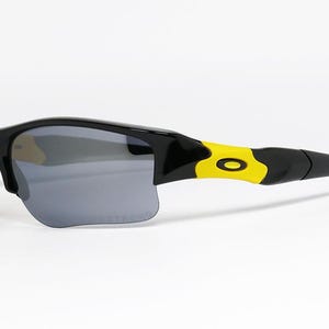 K&ouml;nnte beinhalten: Schwarze und gelbe Sportsonnenbrille mit grauen Gl&auml;sern. Die Sonnenbrille hat ein schlankes, modernes Design mit einem schwarzen Rahmen und gelben Akzenten an den B&uuml;geln. Die Gl&auml;ser sind dunkelgrau und bieten Sonnenschutz.