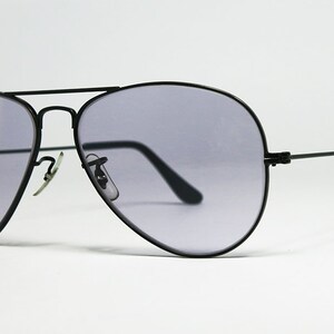 May include: Black aviator sunglasses with gray lenses. The sunglasses have a thin metal frame and are designed for both men and women.