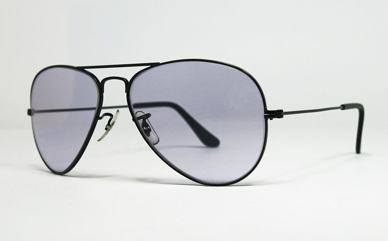 May include: Black aviator sunglasses with gray lenses. The sunglasses have a thin metal frame and are designed for both men and women.